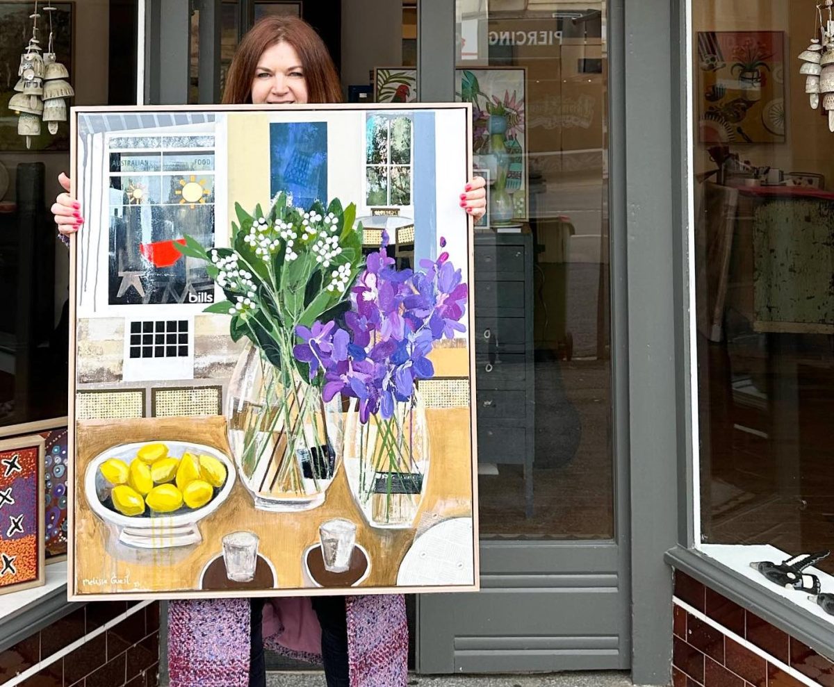 woman holding artwork in front of shop