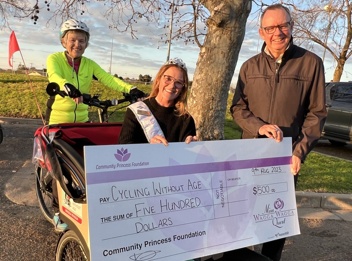 Haylee Birkinshaw hands over a cheque to Neil Wright while Helen Sturman pilots the trishaw.