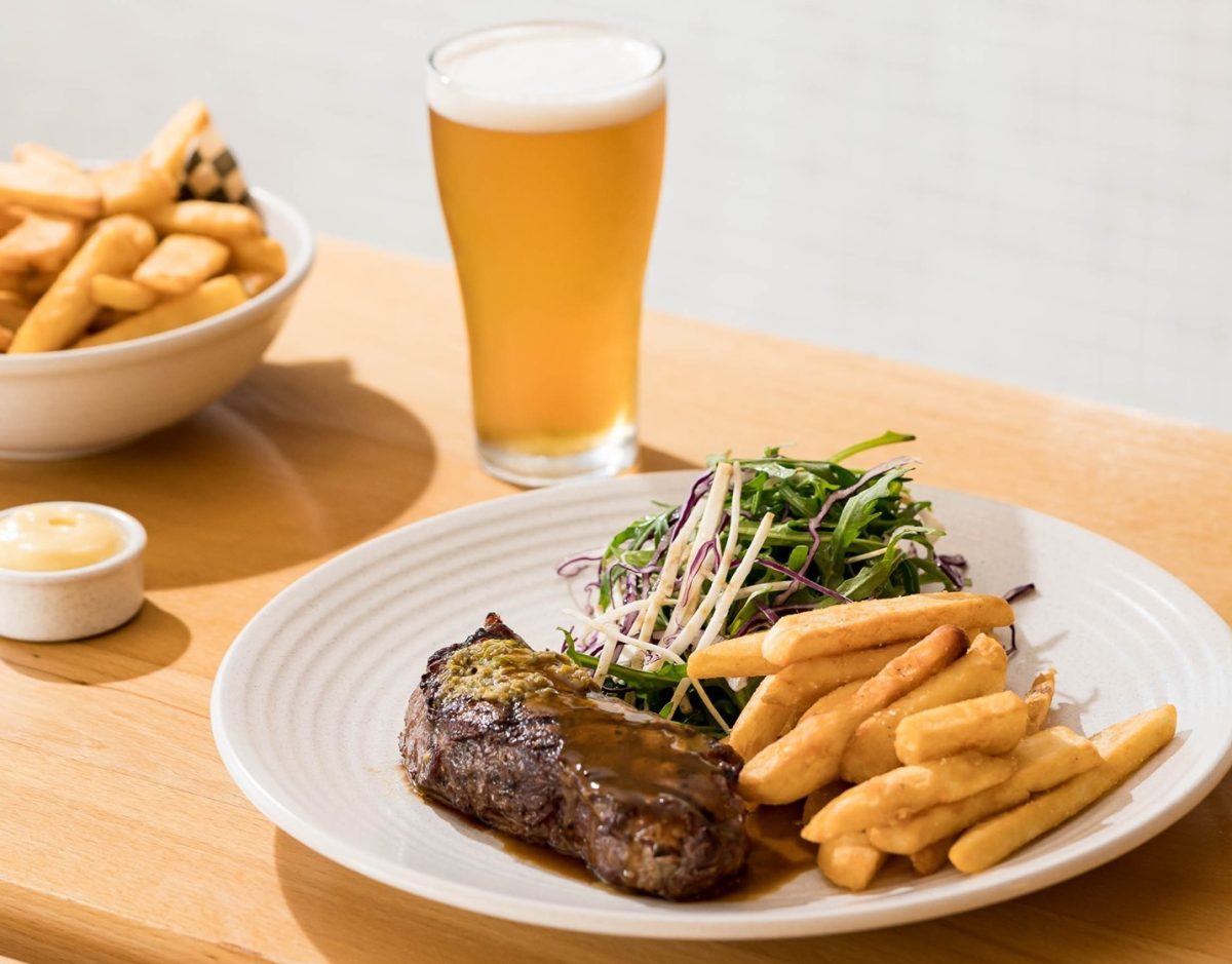 steak with chips and salad next to a beer on a benchtop