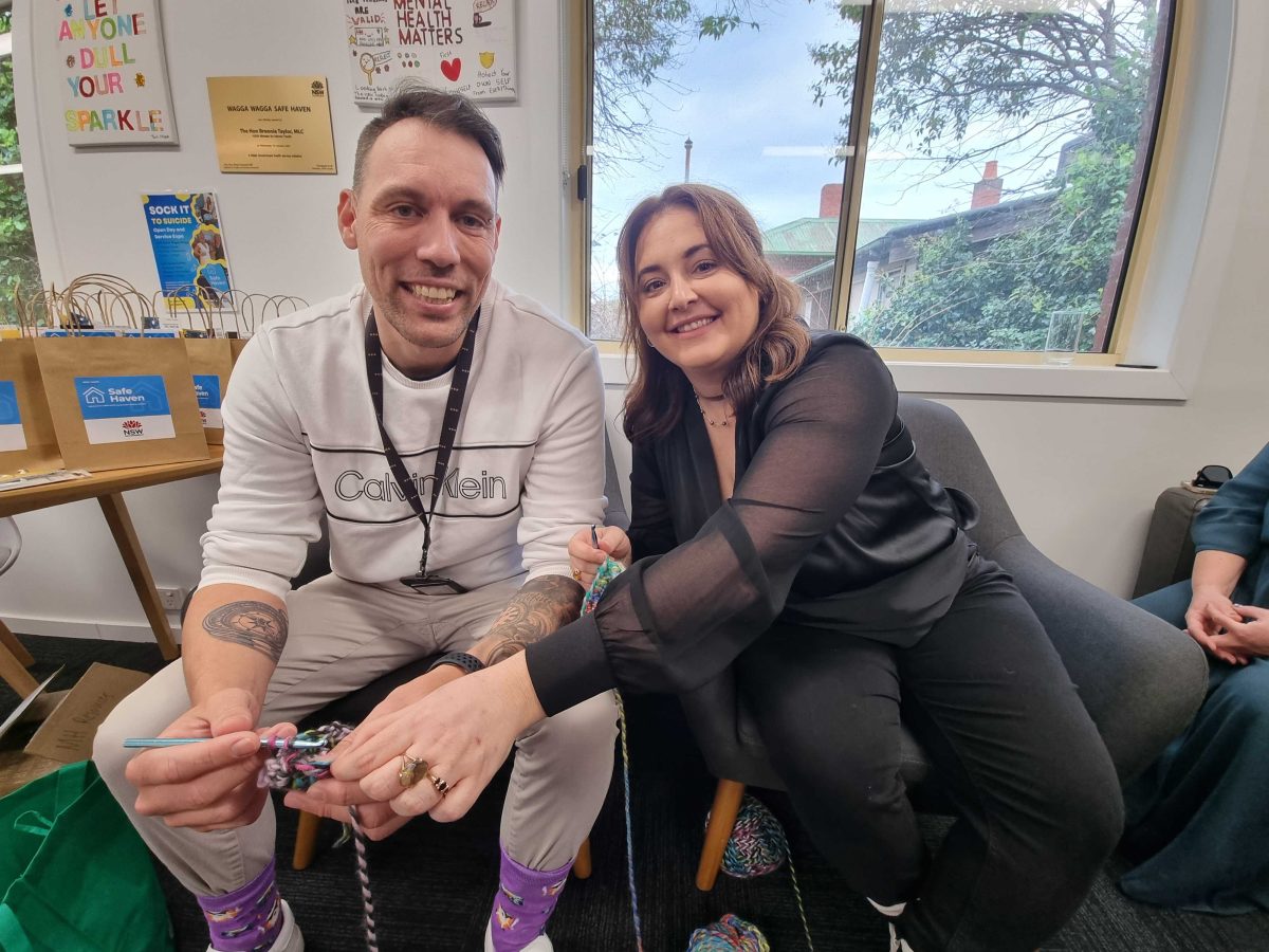 Senior support worker for Wagga and Griffith Safe Haven Jesse Warran-Rigby crocheting the novelty sock for World Suicide Prevention Day with Wagga Safe Haven peer support worker Lauren Demaj.