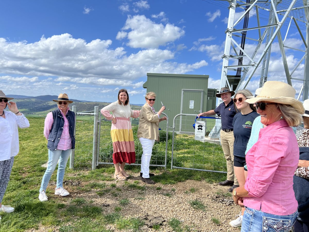 Tooma community members gather with Telstra representatives under blue skies to cut the ribbon on the town's very own tower
