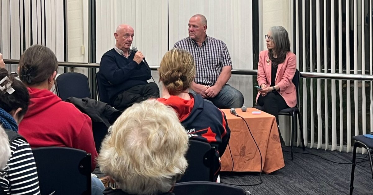 Tim Costello on a table speaking at an event 
