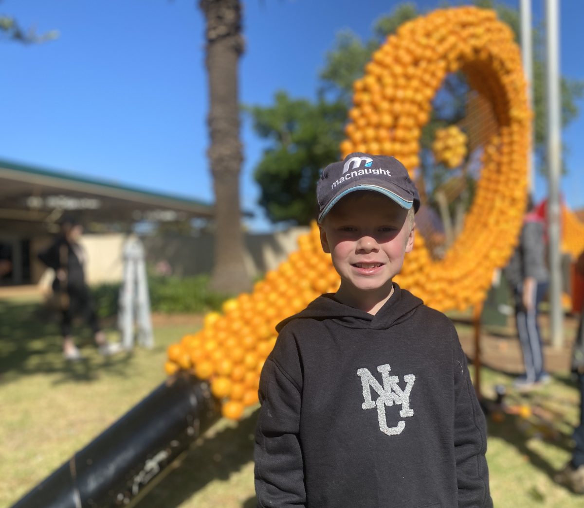 boy and giant sculpture made from oranges