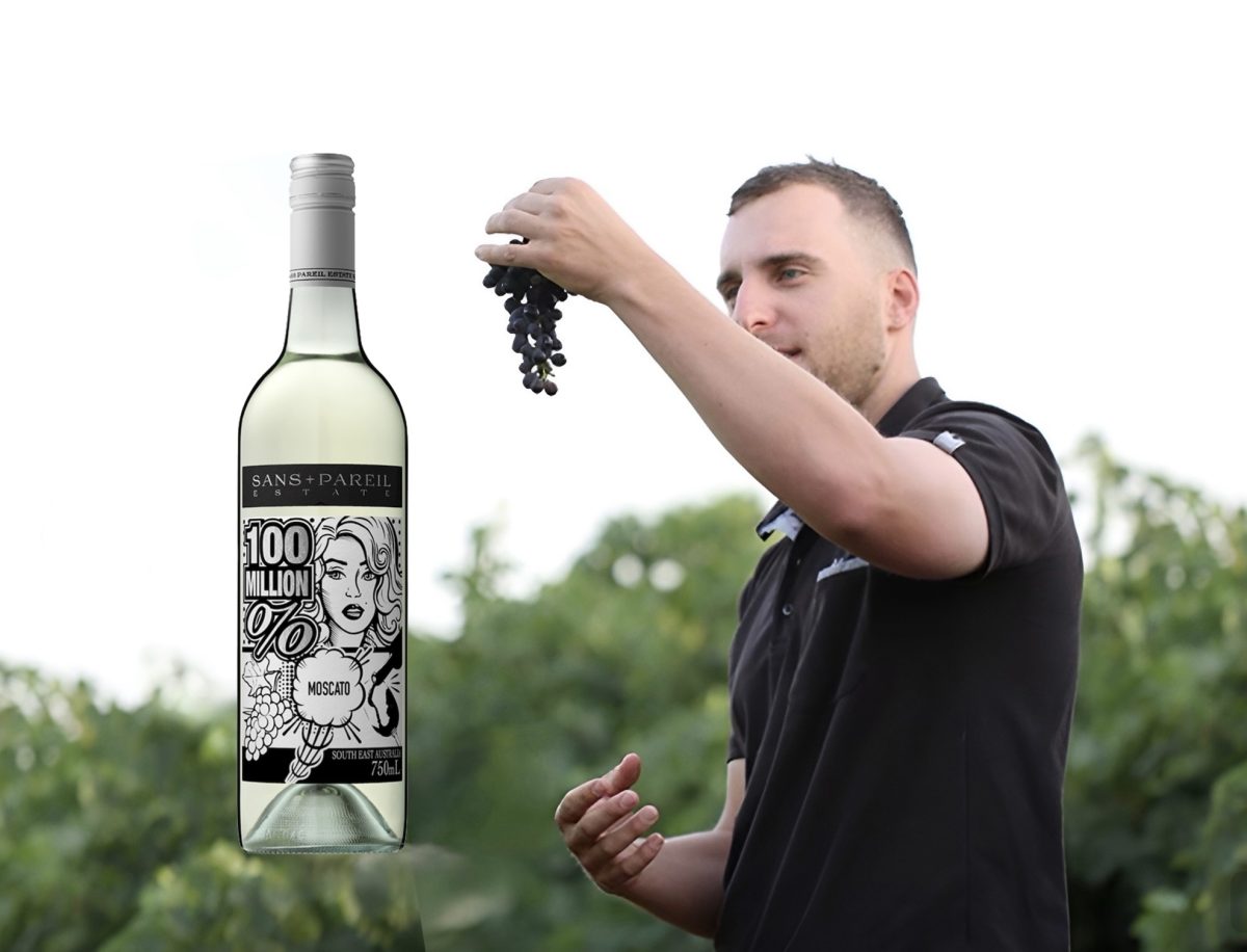 Man holding grapes next to a wine bottle 