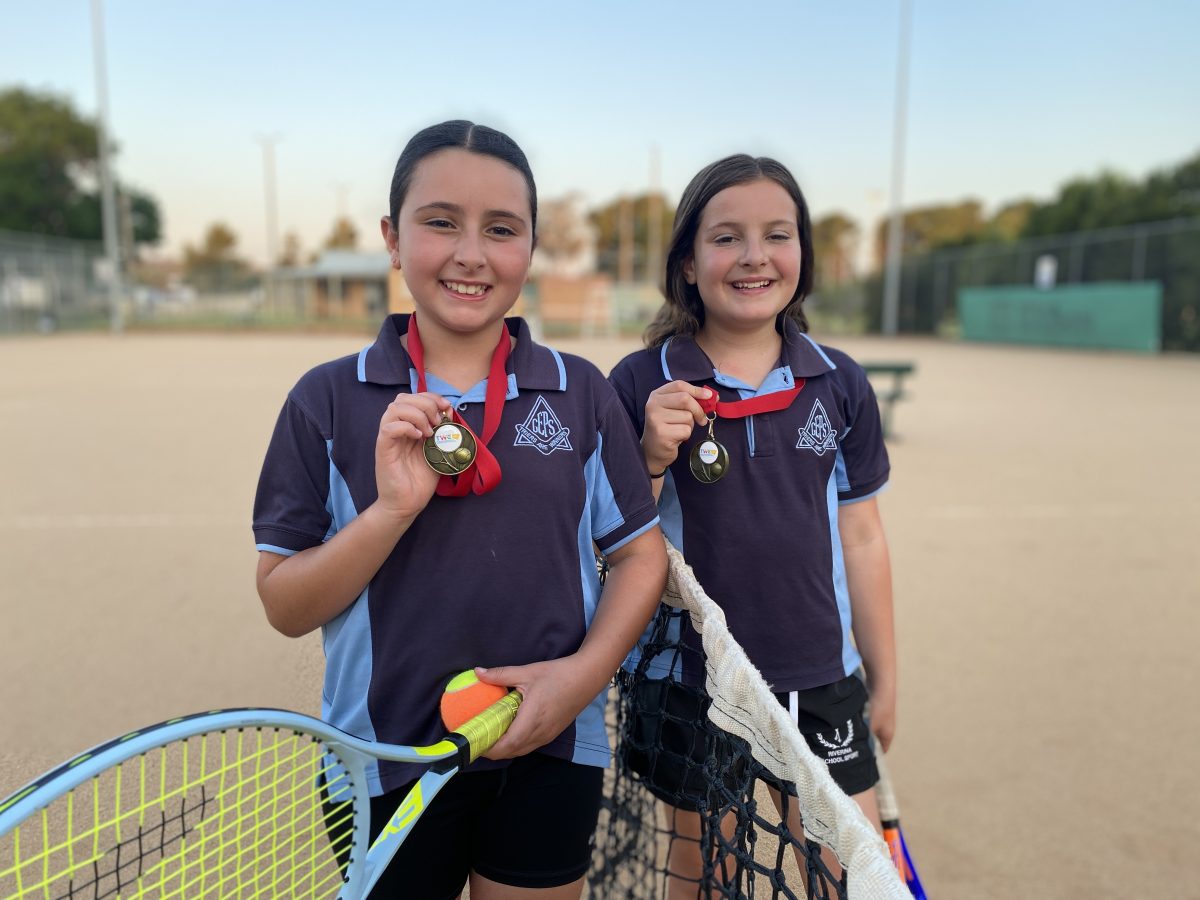 two girls with tennis racquets and medals 