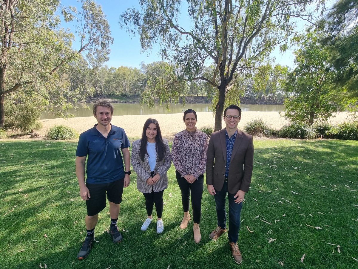 four people standing near river