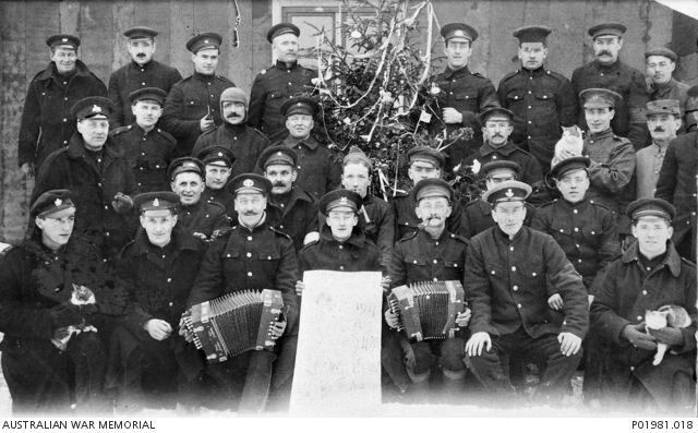 POWs in black dyed uniforms gathered around a Christmas tree