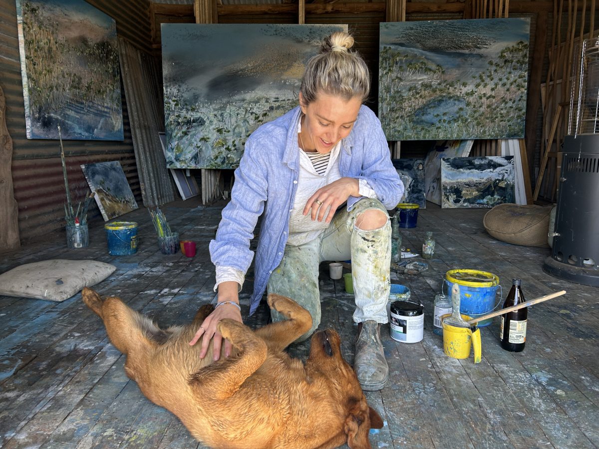 Artist in studio playing with dog