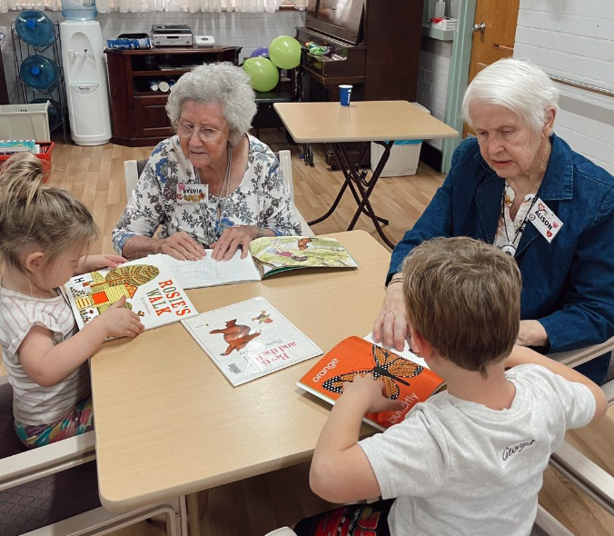 The preschoolers and their 'elderly friends' enjoy reading together.