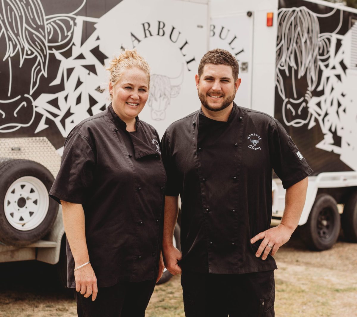 woman and man standing in front of their catering business vehicles