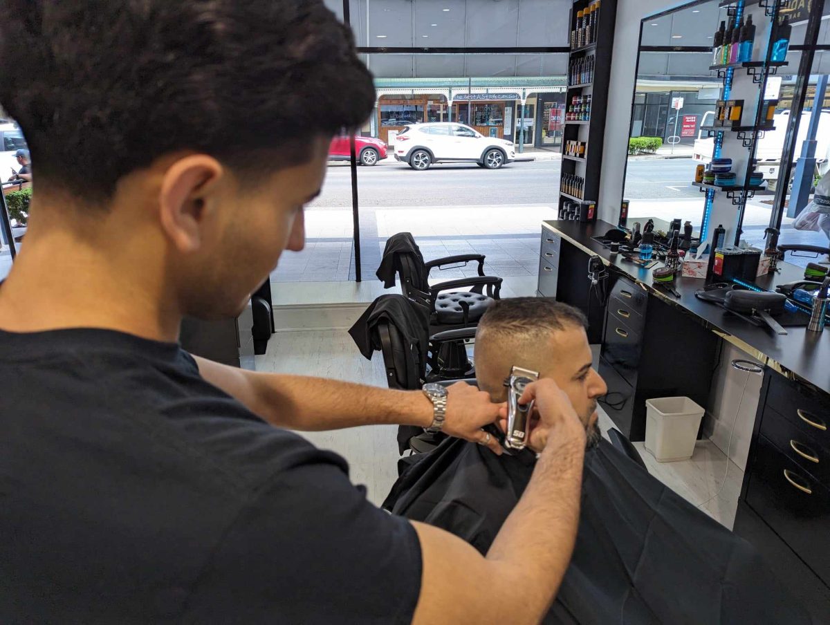 Adil giving a customer a haircut