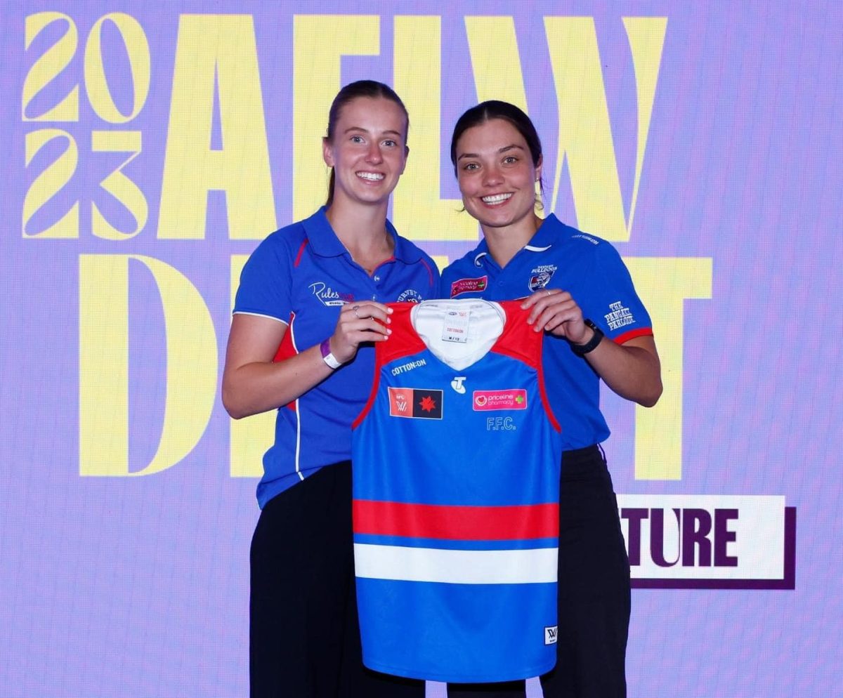 two female Aussie rules players holding a guernsey