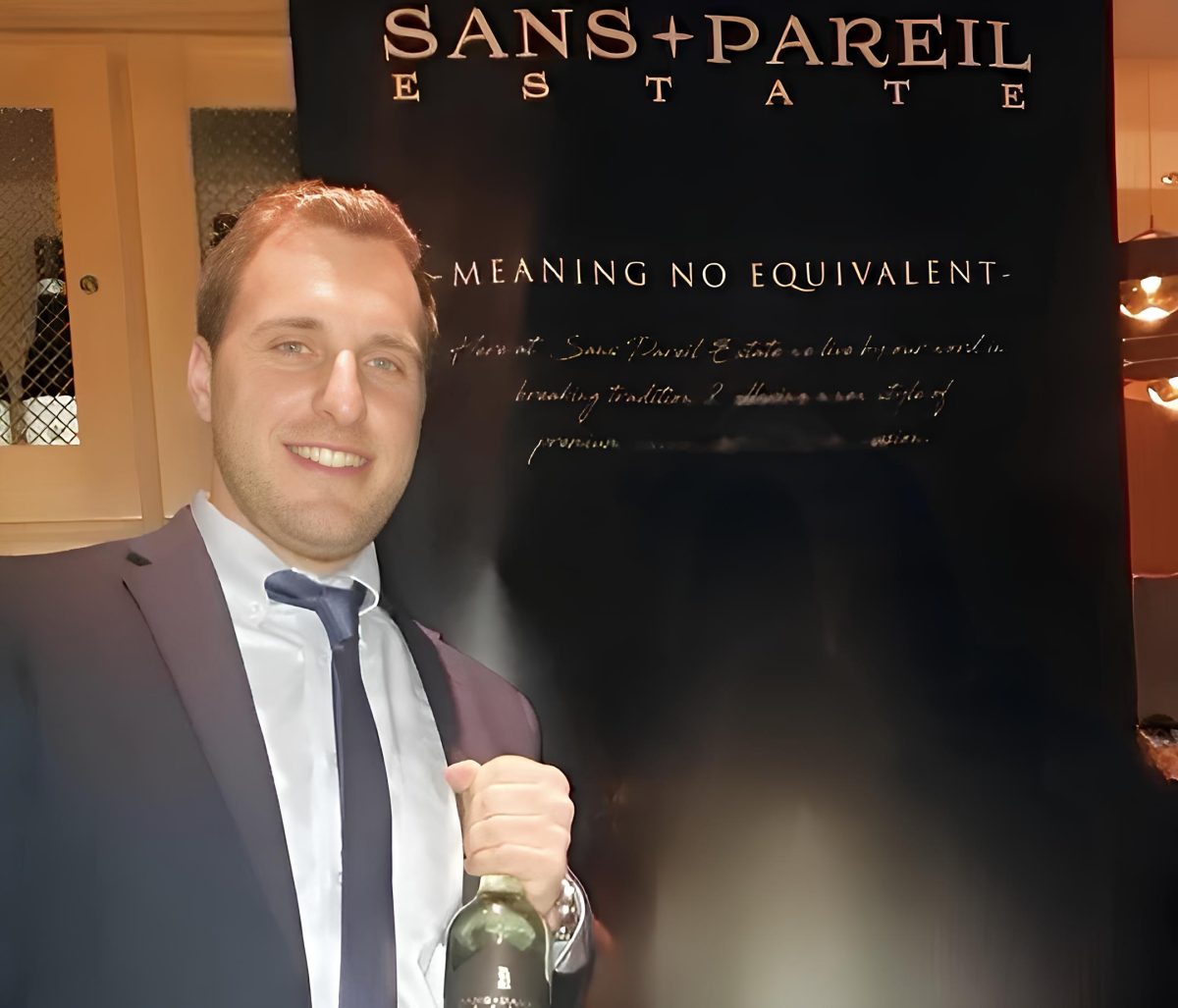 man holding wine bottle next to sign 