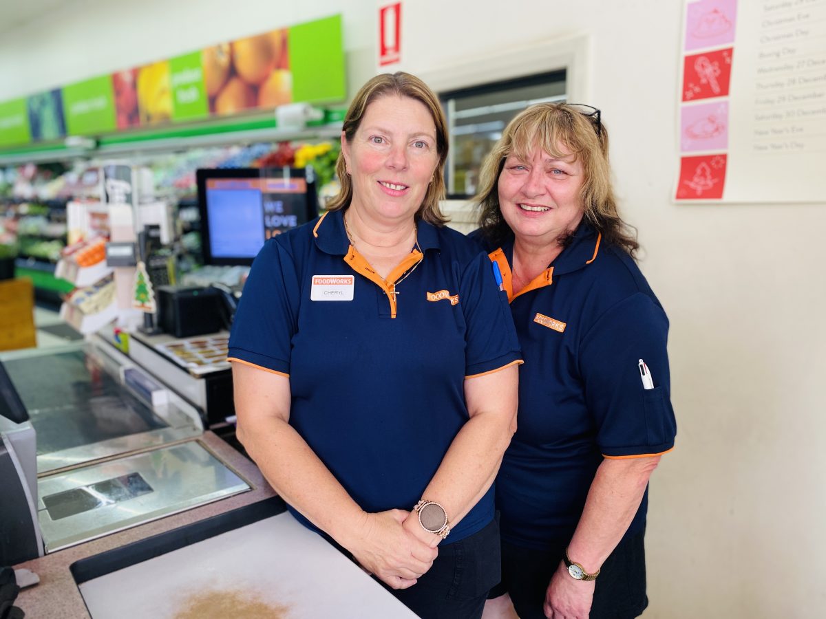 two women standing at supermarket checkout 
