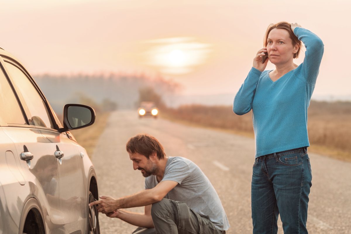 man and woman with broken-down car on highway
