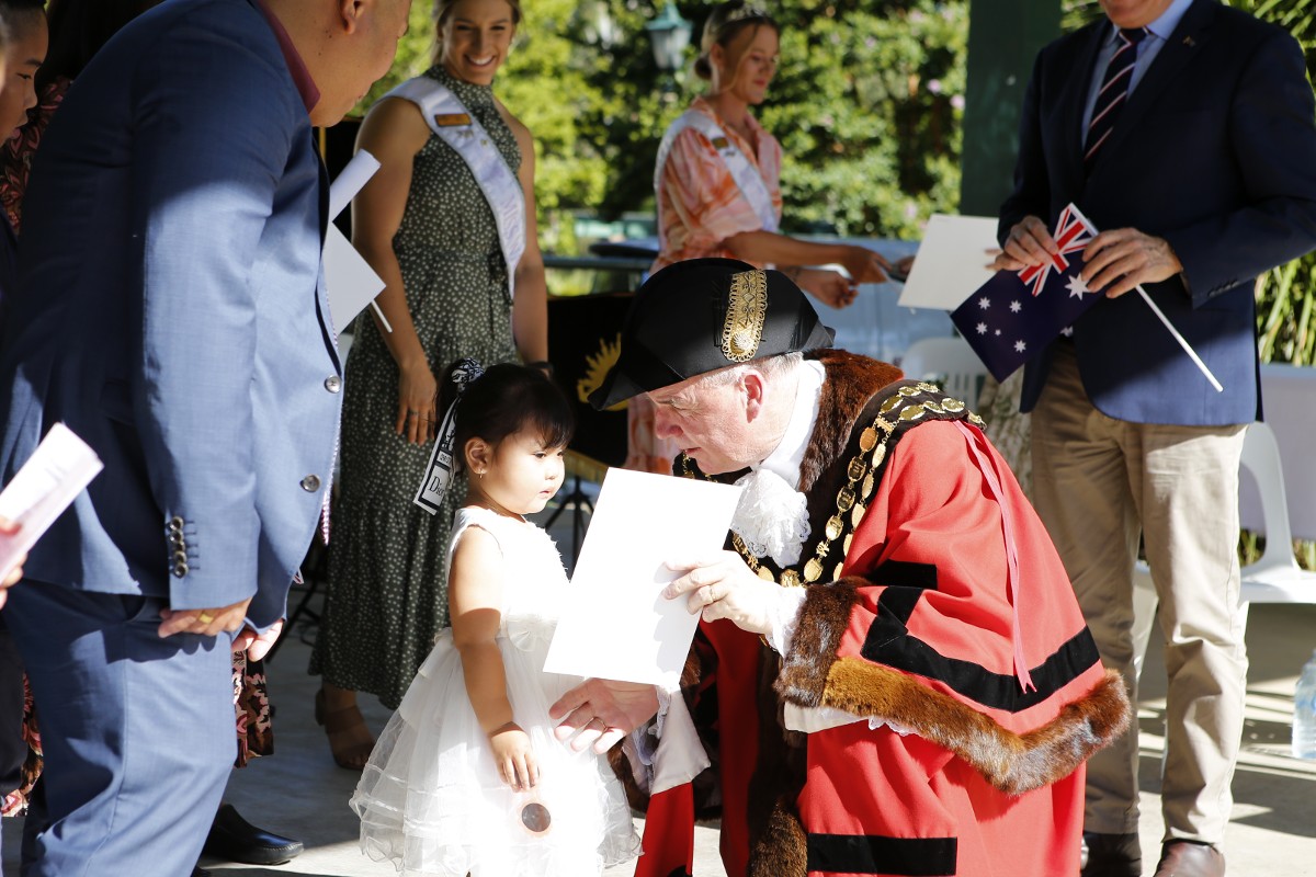 Wagga Wagga mayor Dallas Tout presenting a citizenship certificate to a young girl
