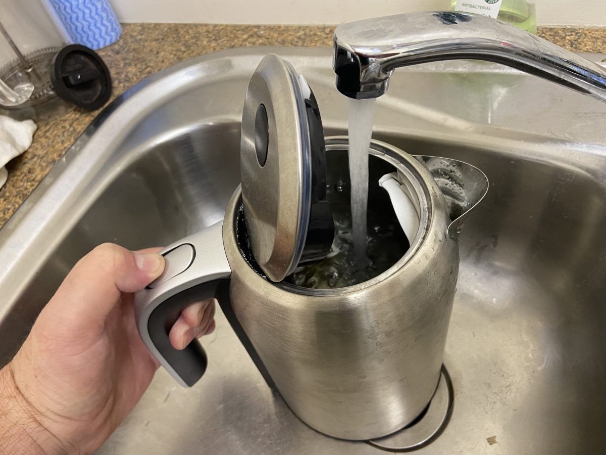 filling kettle with water at kitchen sink