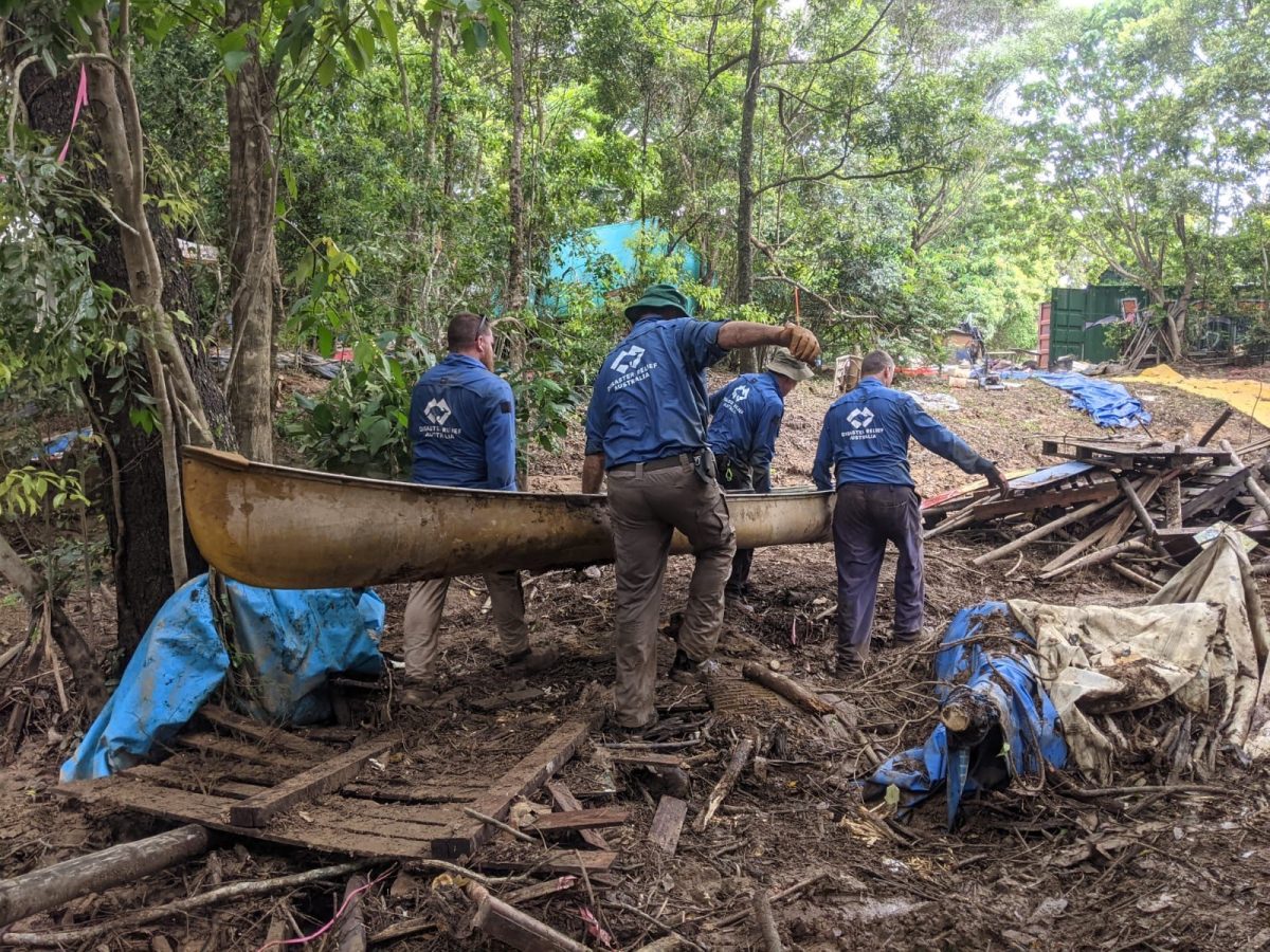 men caryying a canoe in flood-damaged area