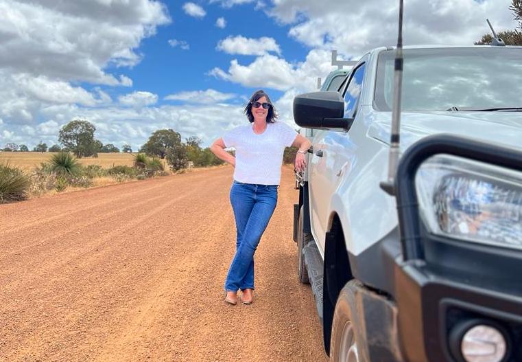 woman leaning against ute on dirt road