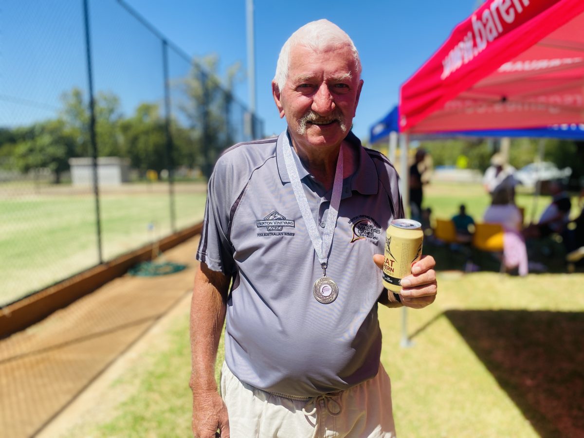 elderly man with a can of beer and medal around his neck