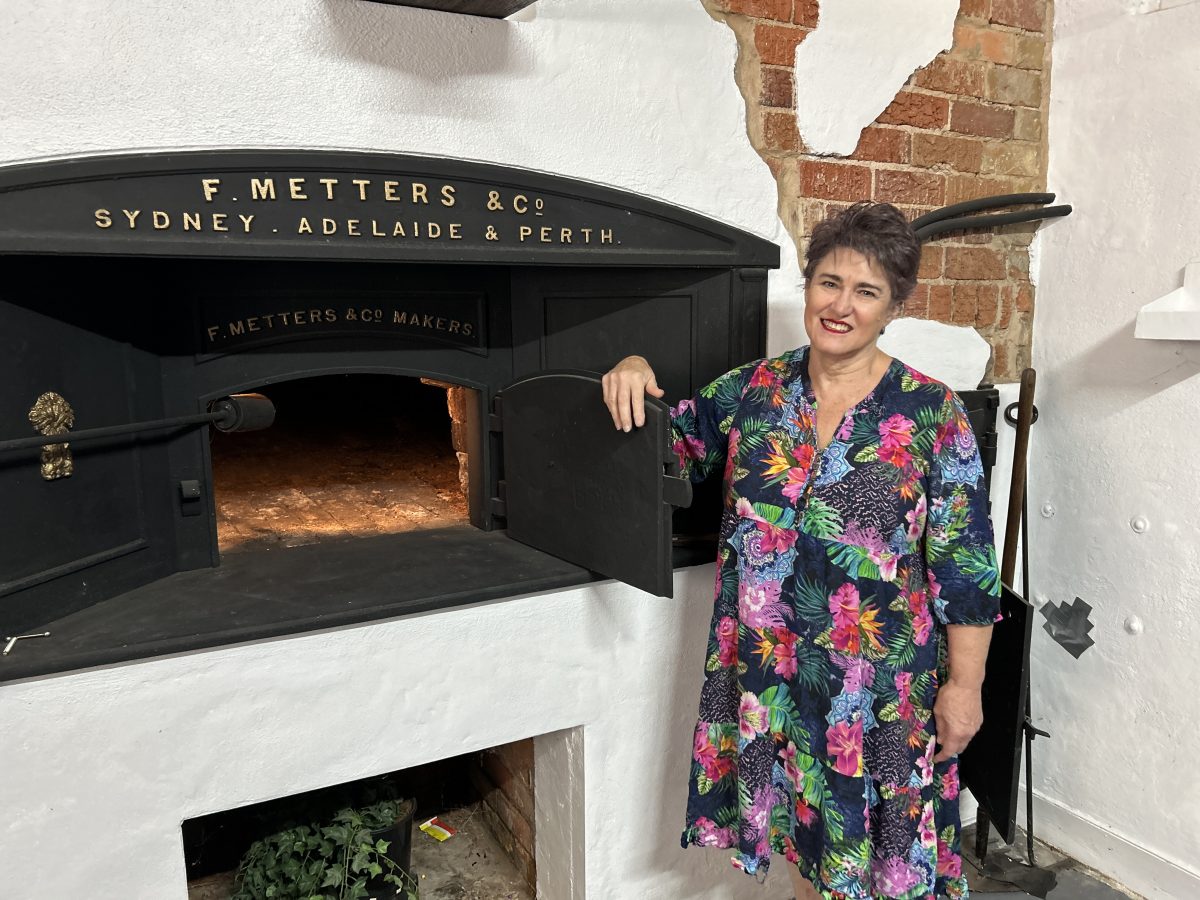 Woman stands in front of historic bread oven