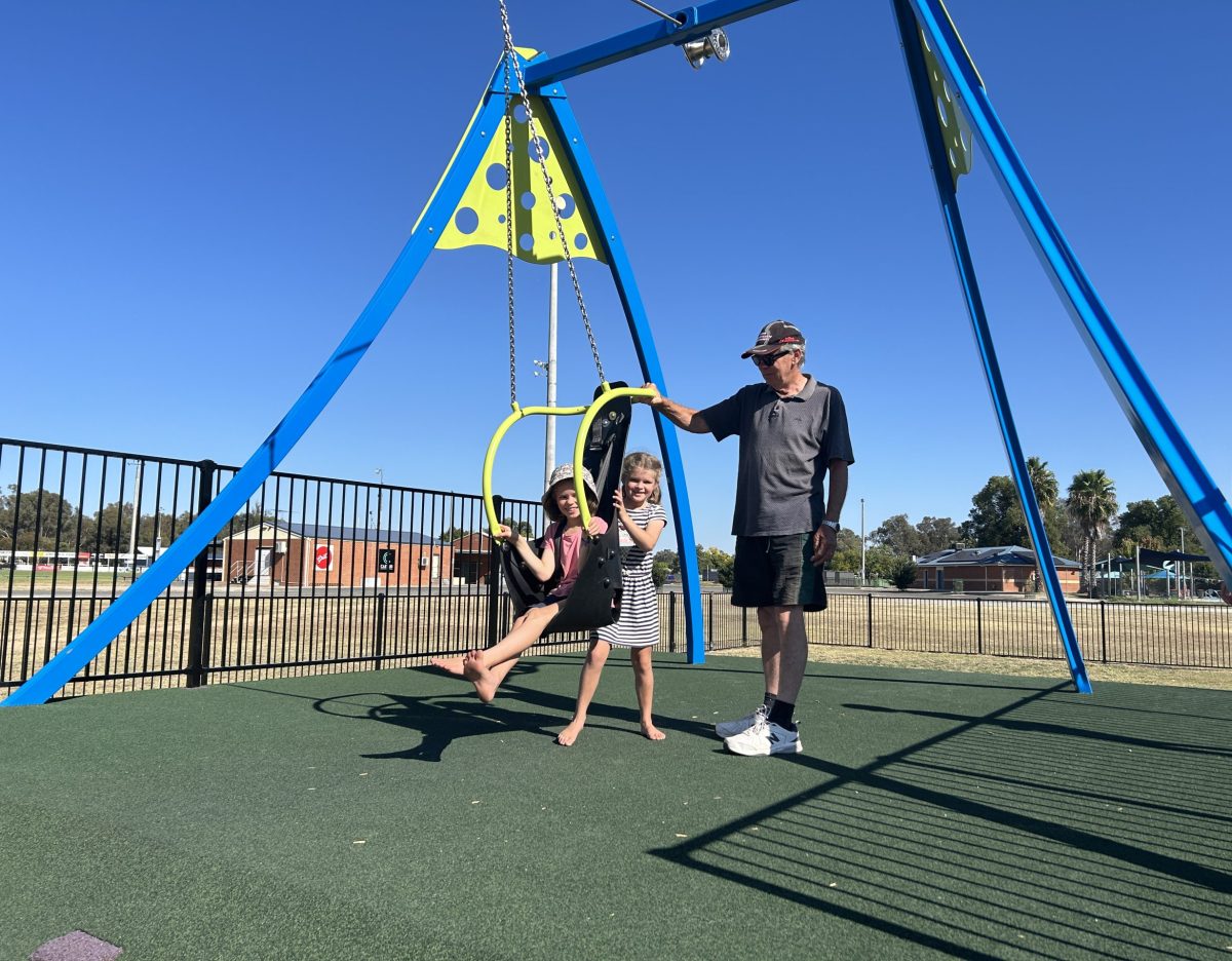 Man holds swing with two children on it