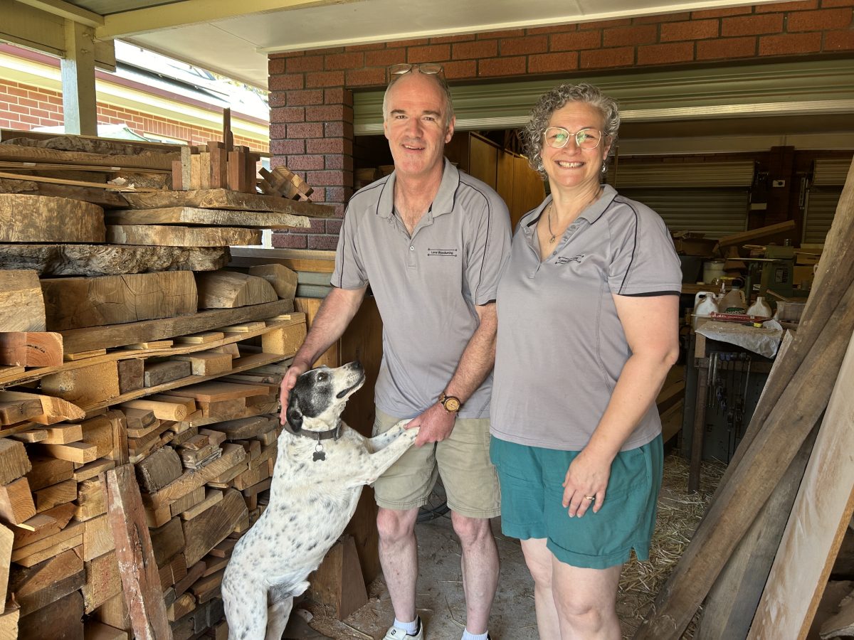 Man and woman in woodshed with their dog