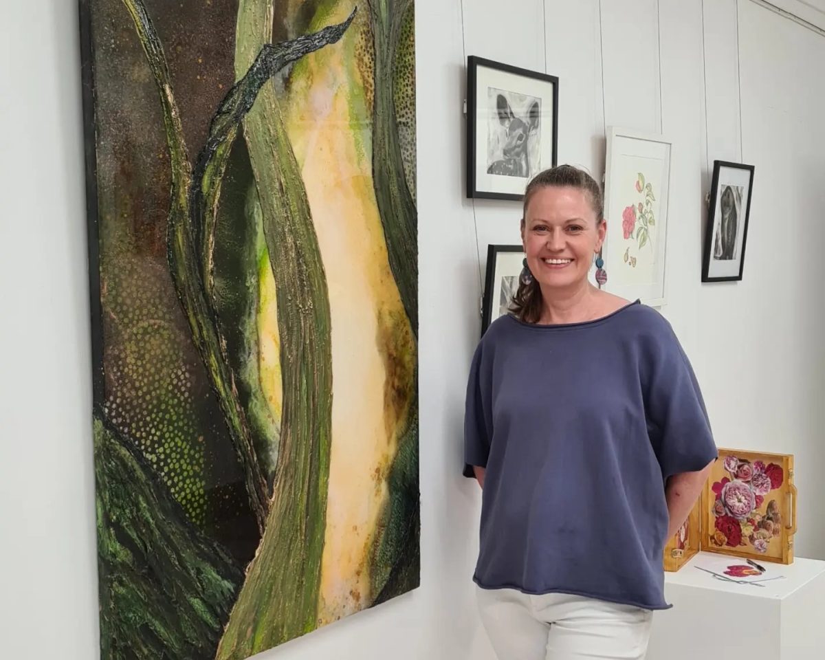 Woman stands in front of the artwork she has produced