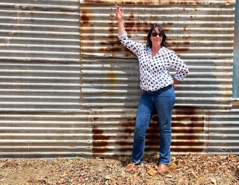 A woman standing next to a corrugated-iron wall