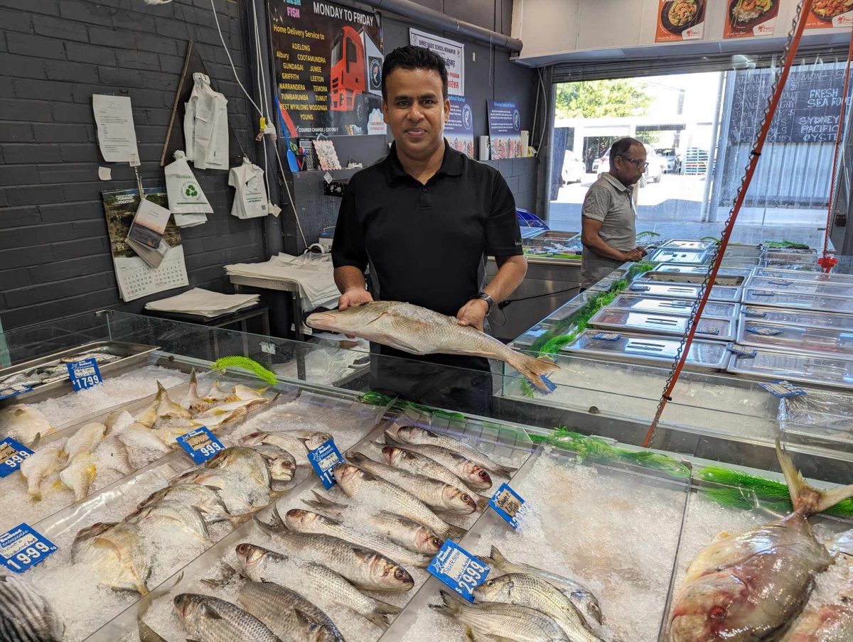 man holding a fish at his seafood market