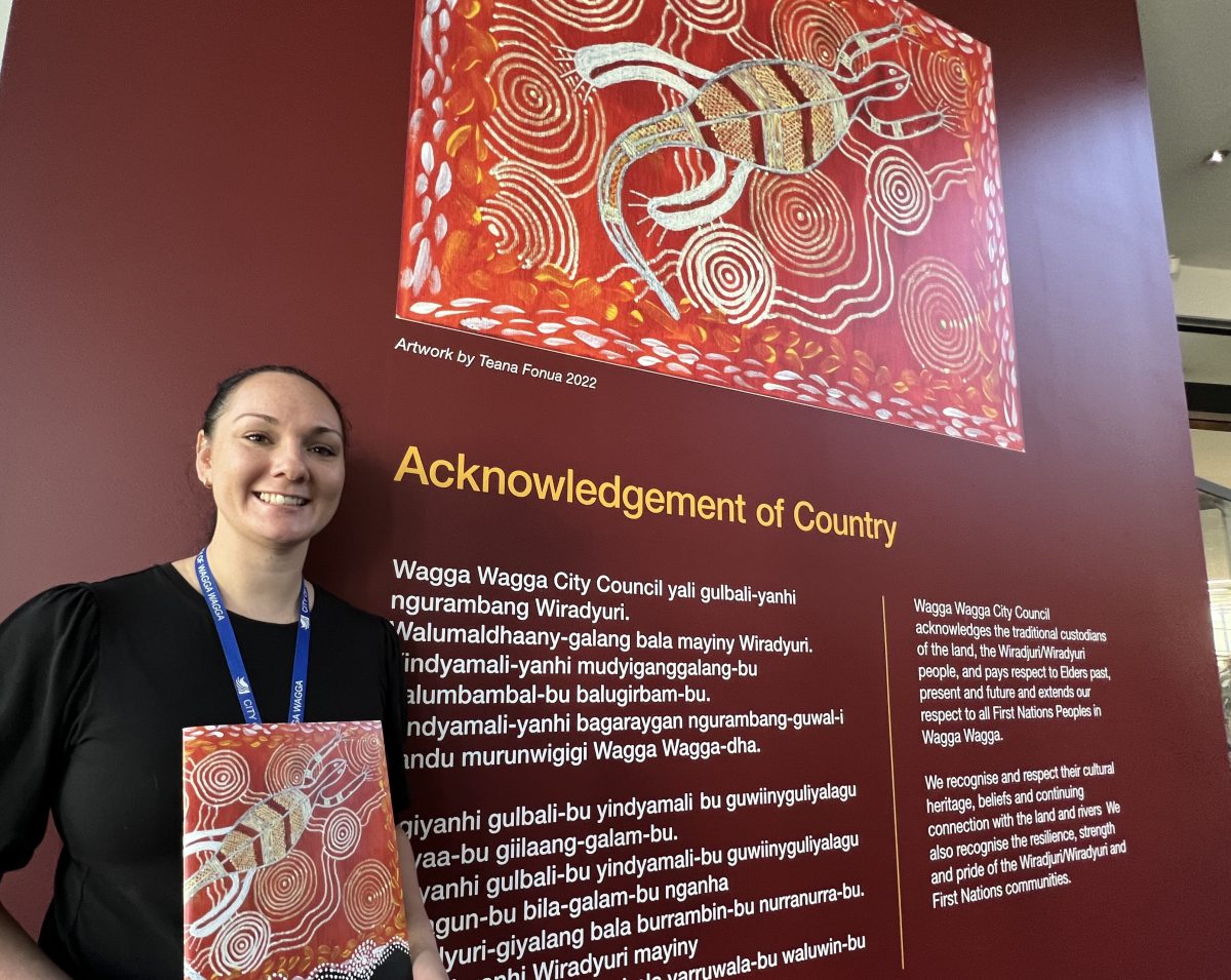 woman with sign and Indigenous artwork