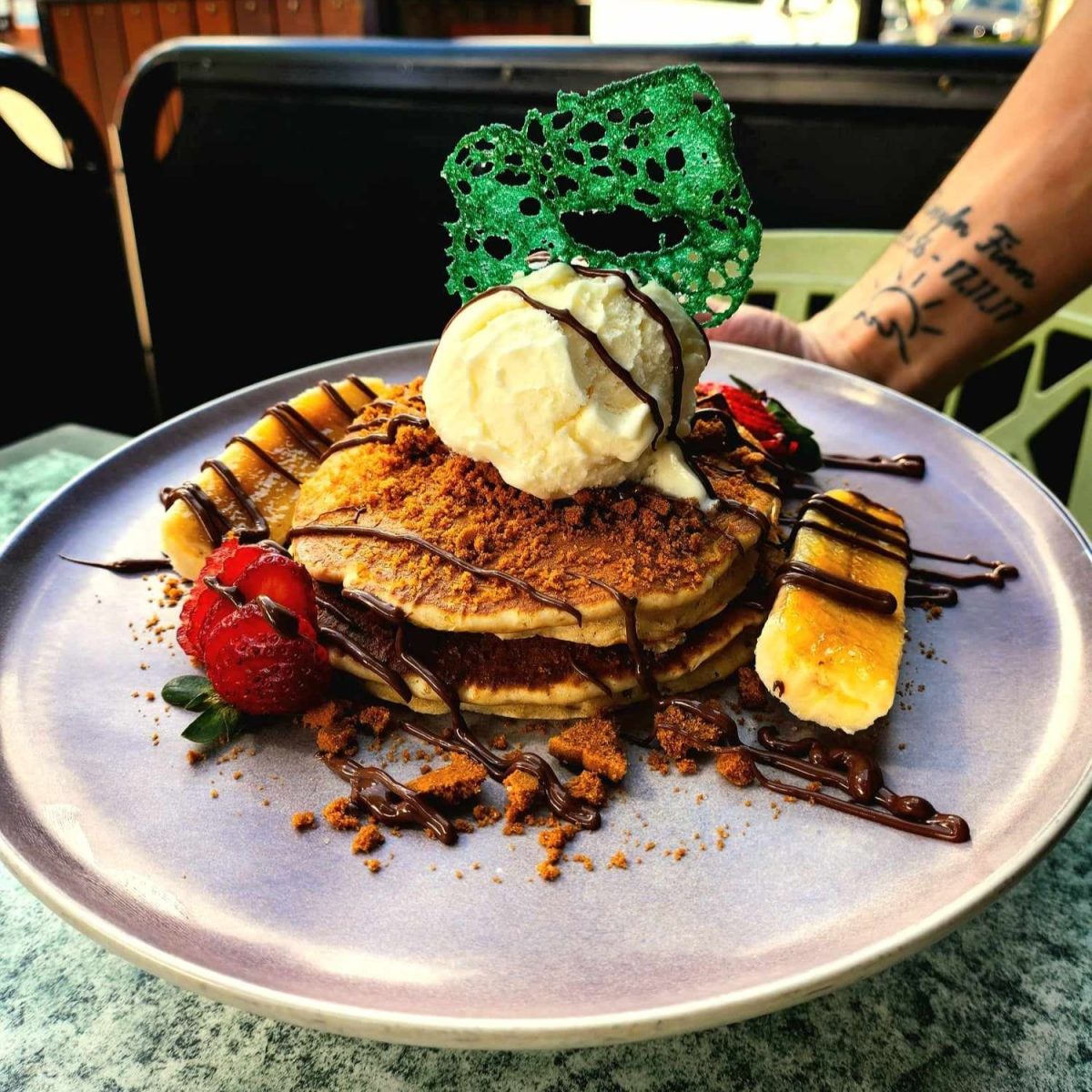 Biscoff pancakes with Nutella, banana, strawberries, cream, ice-cream, butterscotch and pistachio tuile.
