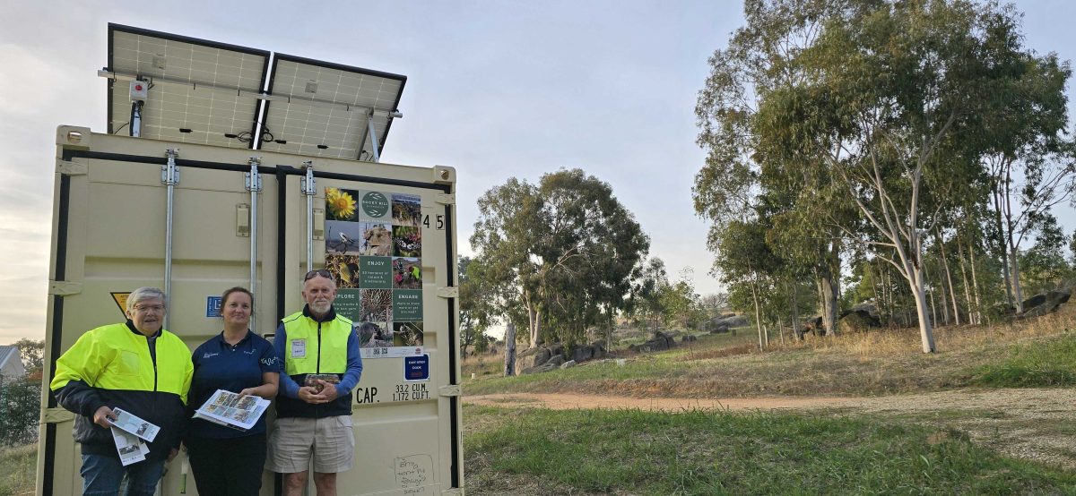 three people in bushland with Rotary brochures