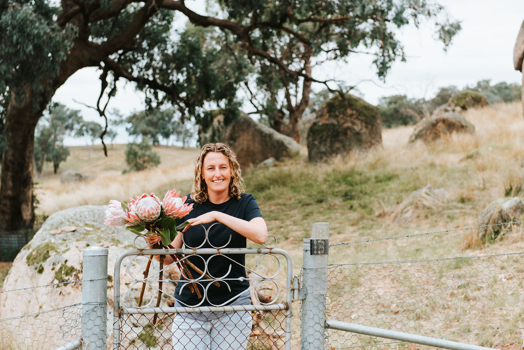 woman holding flowers at farm gate