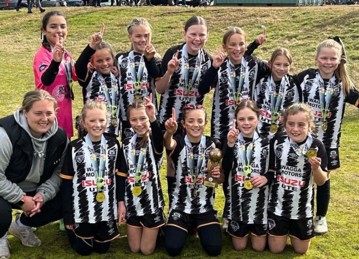 junior girls' soccer team with medals and trophies