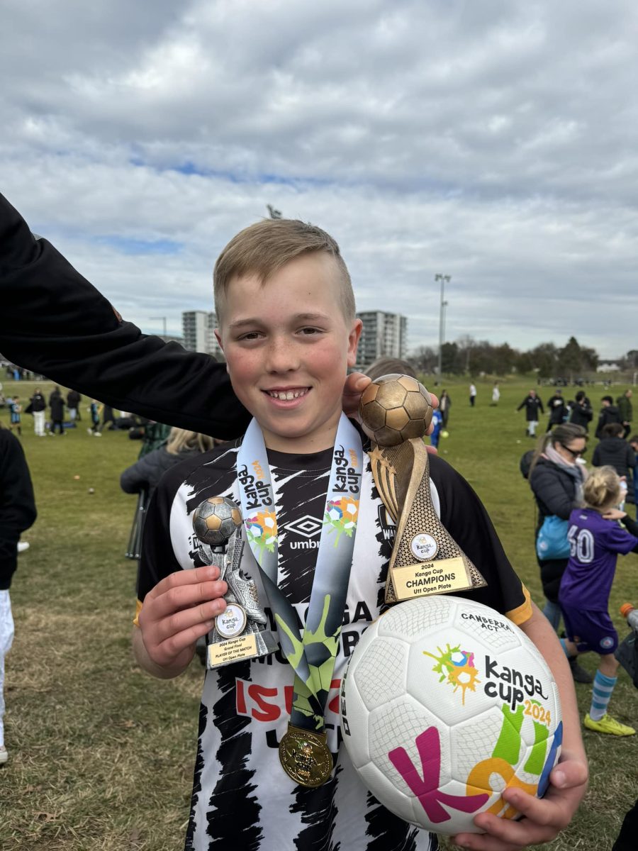 young male soccer player with trophies, medal and ball 