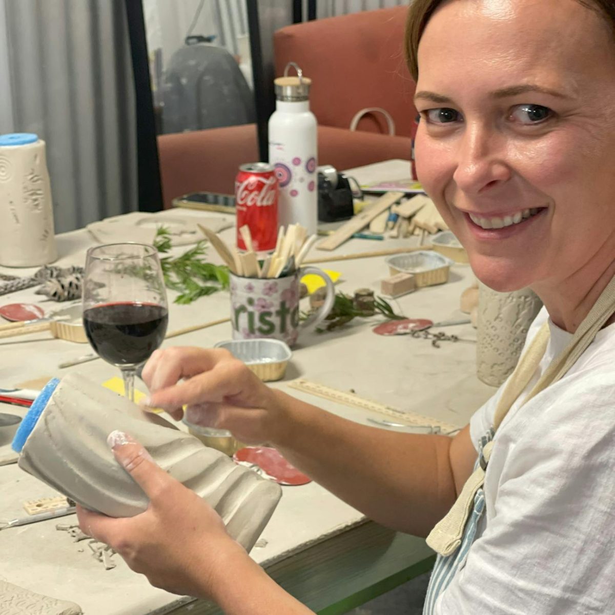 A woman having a glass of wine at a pottery workshop