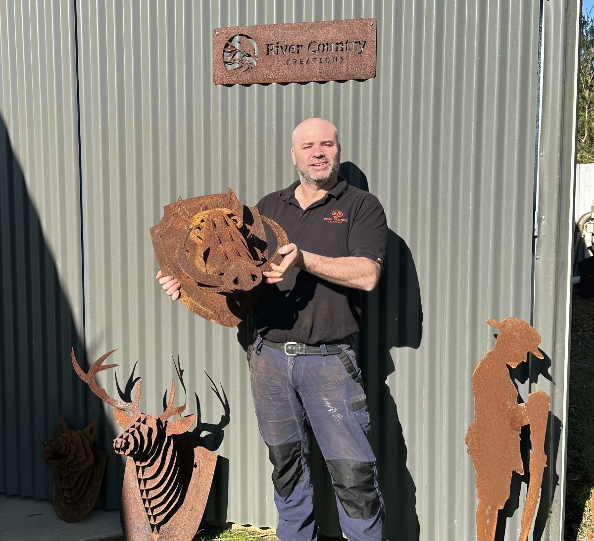 Man stands with piece of laser cut iron artwork