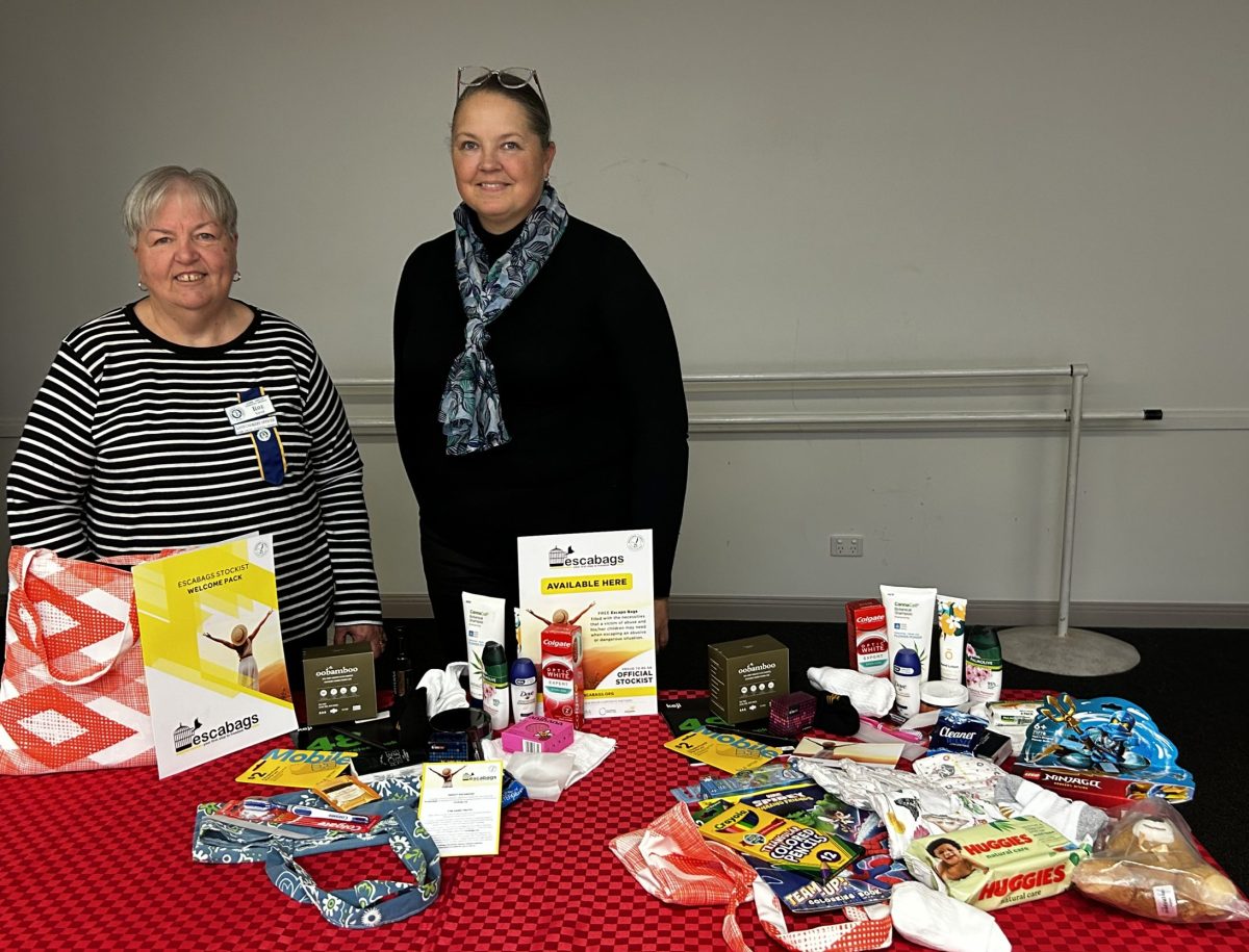 two women standing behind a table of goods