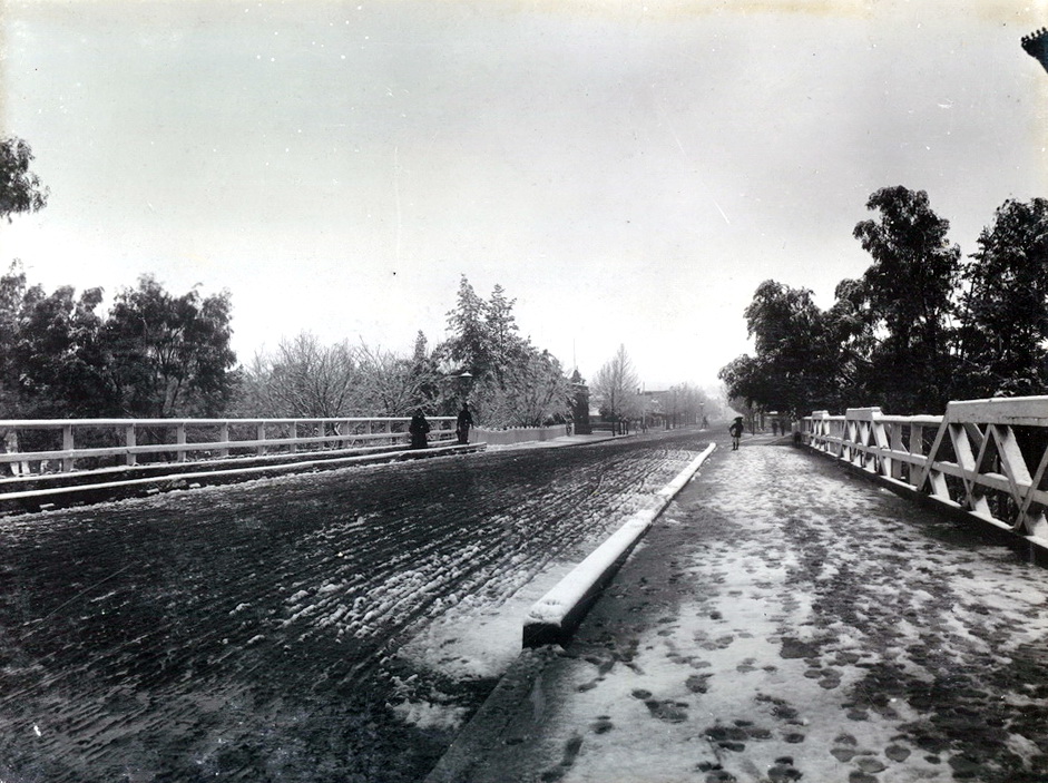 old photo of snow on a small-town bridge