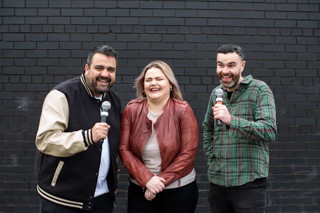 two men with microphones and a laughing woman