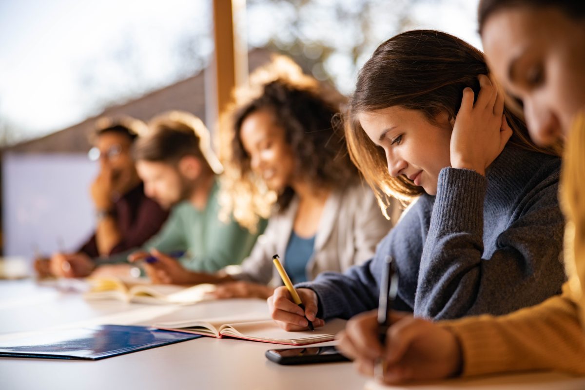 Smiling college student writing during a class at the university.