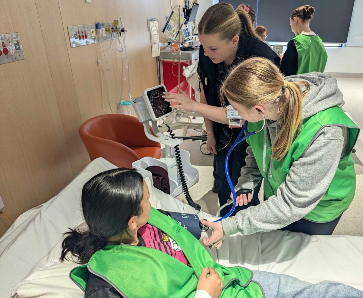 Year 11 Wagga High student Darnee Doherty (middle) teaching Billabong High School student Kiera Morgan (left) and Leeton High School student Brooke Pearce (right) how to measure blood pressure.