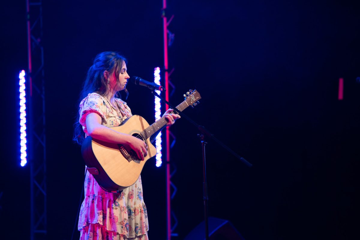 Woman on stage singing and playing guitar