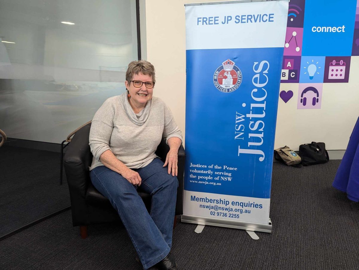 A woman sitting next to a sign