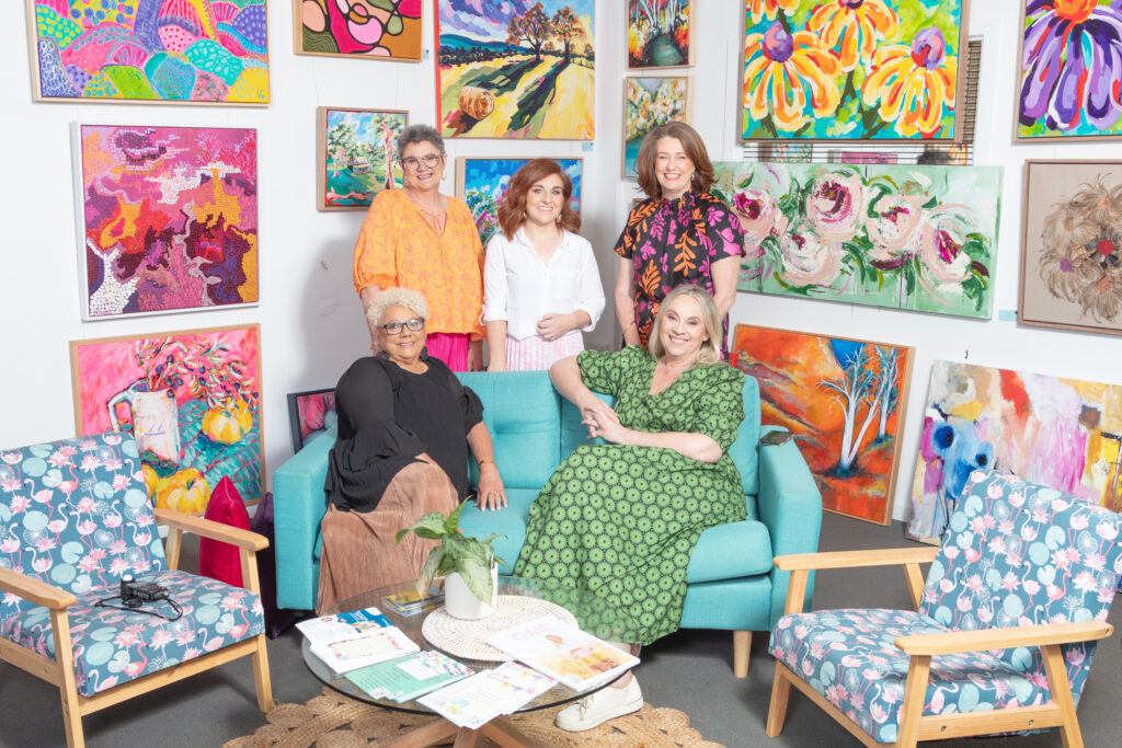 Artists on couch surrounded by paintings