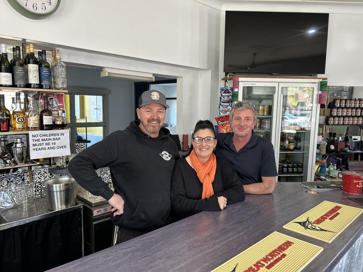 Three people standing behind the counter at a bar