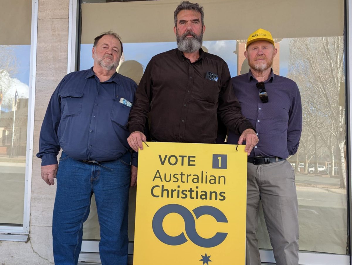 Three men with an electoral placard