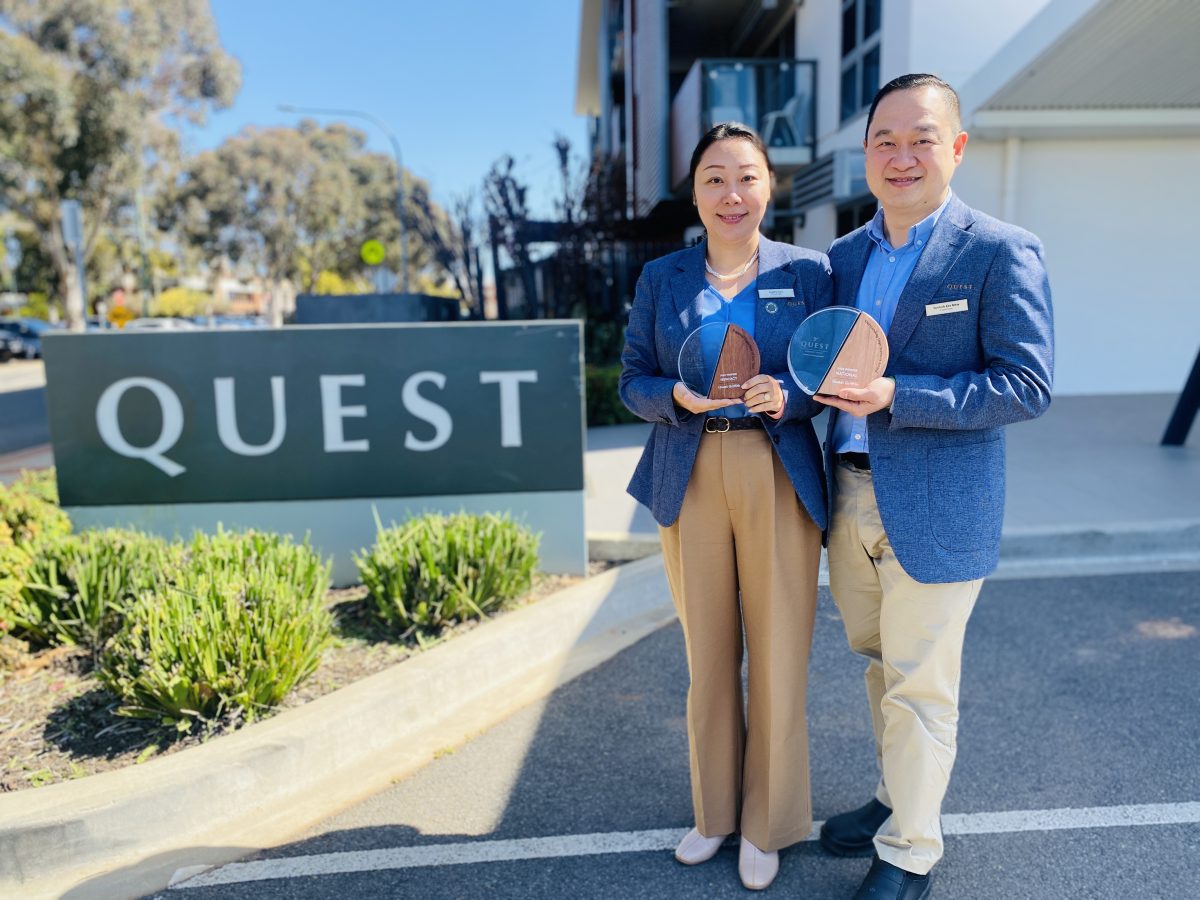 Sophie Sun and Yannick Kee Mew outside Quest sign with awards