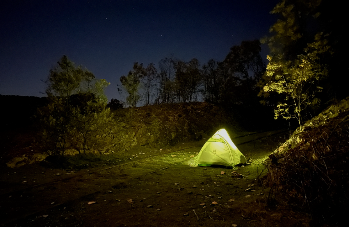 illuminated tent pitched next to a disused railway track